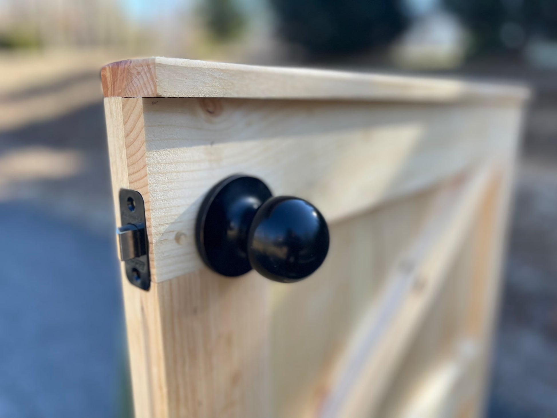 Close-up of black door knob hardware on custom K-frame wooden indoor gate