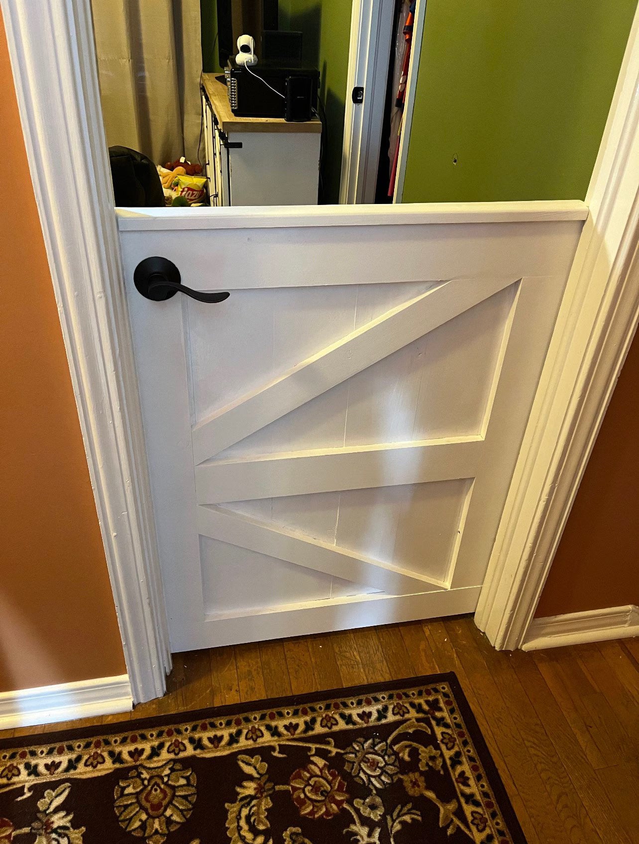 White painted custom K-frame wooden indoor gate installed in a residential doorway